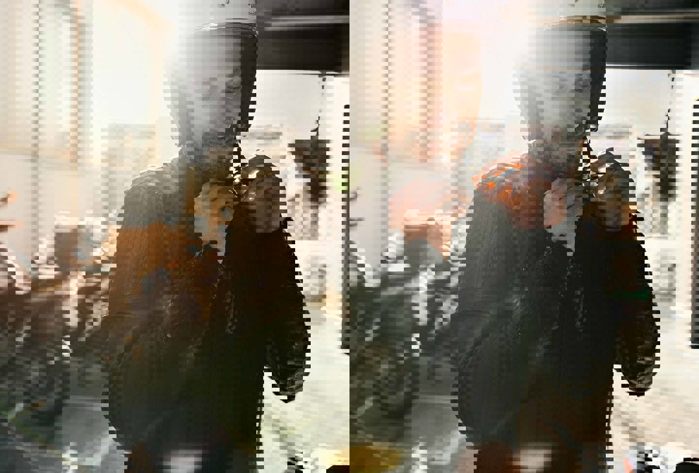 En smilende mand i læderjakke spænder sin motorcykelhjelm, der holder motorcykler parkeret i baggrunden.