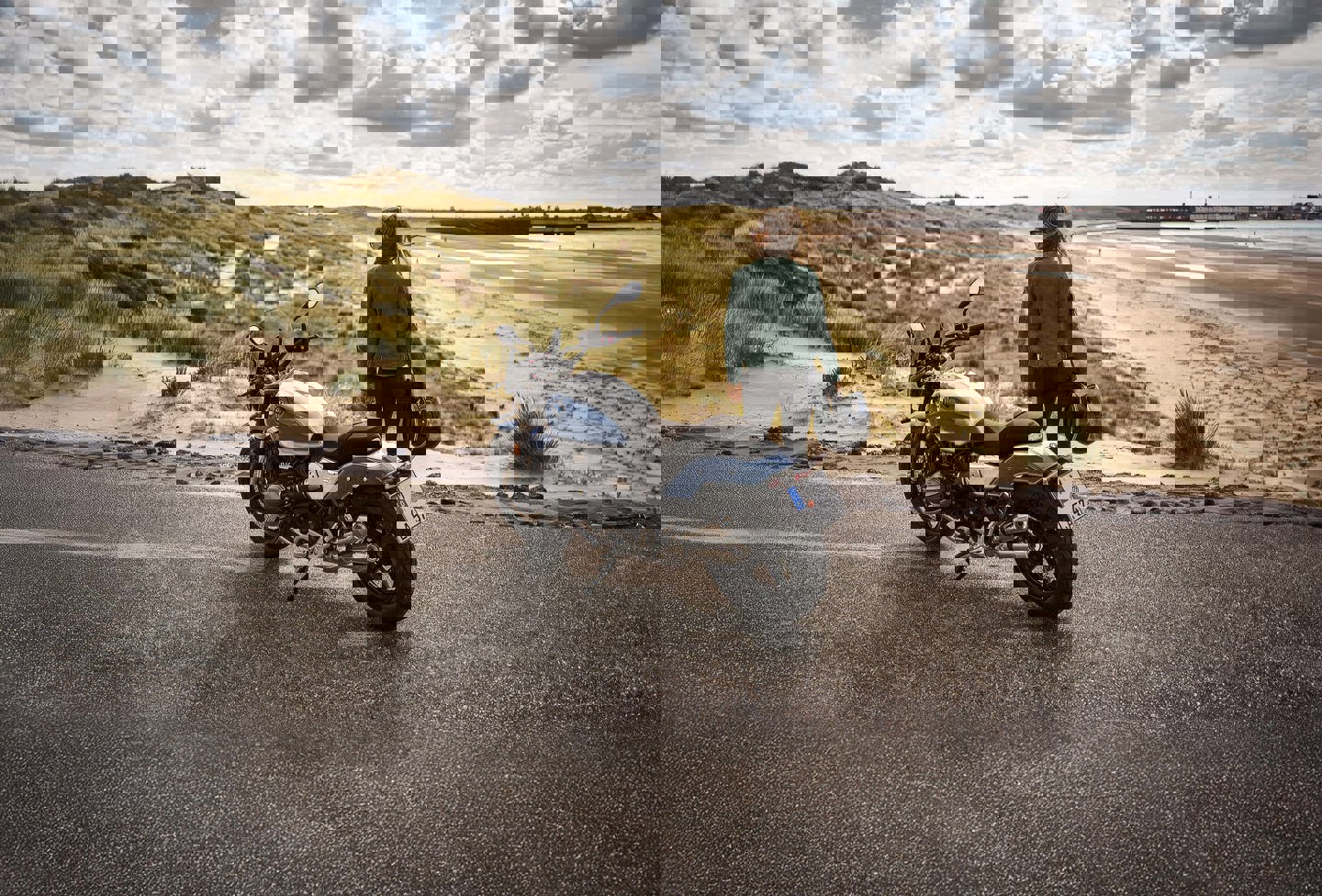 Kvinde står ved BMW motorcykel ved strand