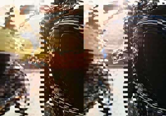 Nærbillede af en sort motorcykel med BMW Logo, i baggrunden ses en gul motorcykel og solskin.