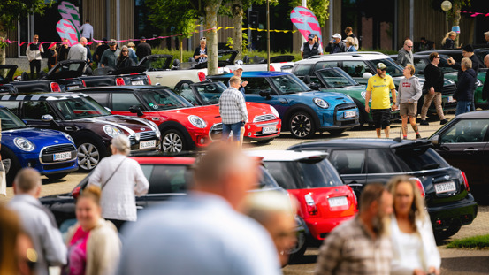 Fyldt parkeringsplads med MINI'er og mennesker.