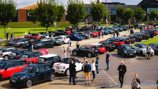 Fyldt parkeringsplads med MINI'er og mennesker.