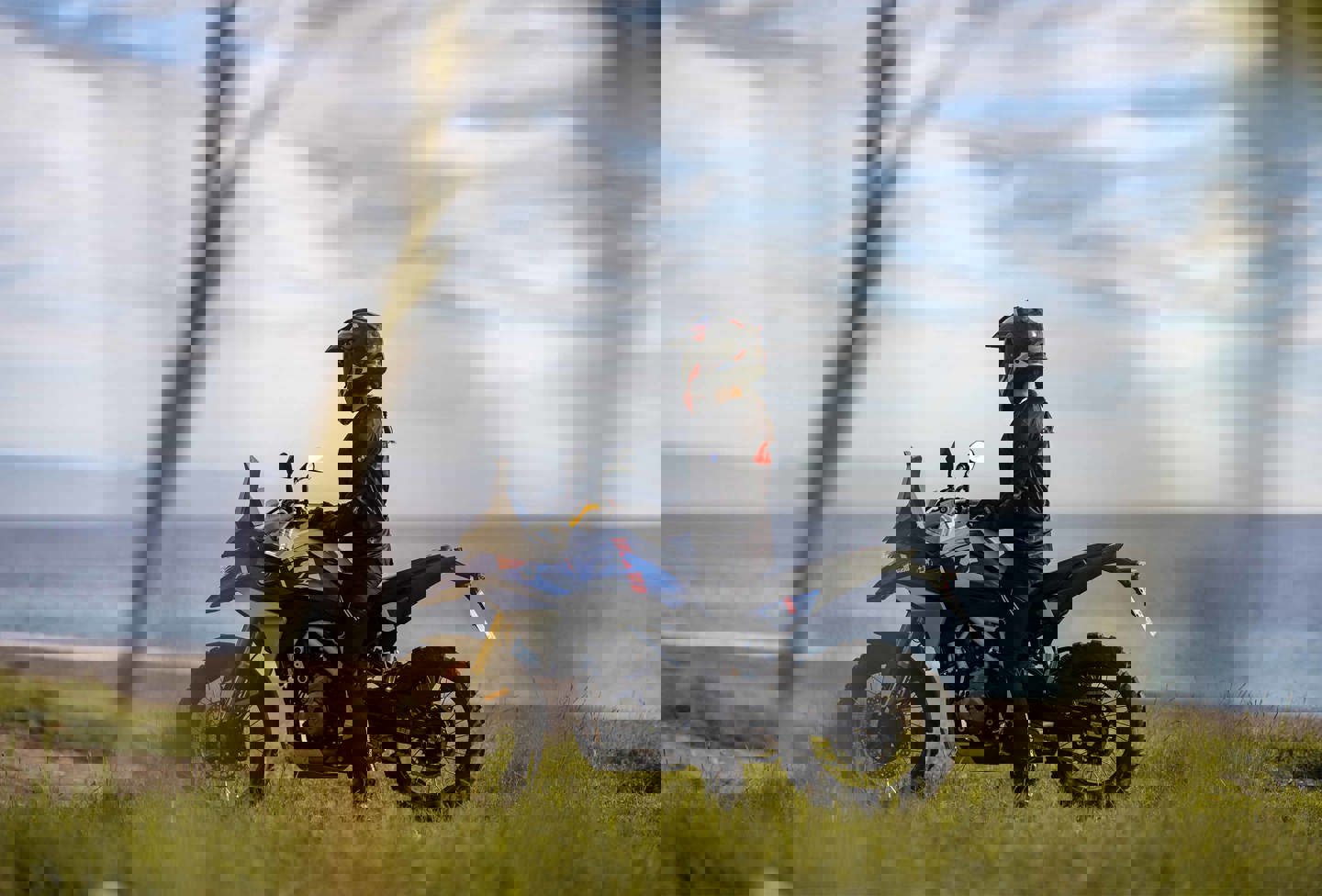 En person holder parkeret på en BMW Motorrad motorcykel på græs nær havet.