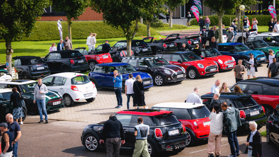 Fyldt parkeringsplads med MINI'er og mennesker.