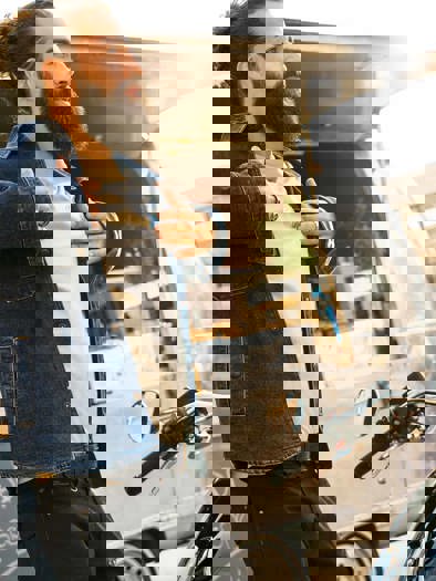 En mand tager sin cowboyjakke på, foran en foodtruck. I forgrunden holder en BMW Motorrad motorcykel parkeret, med en motorcykelhjelm på styret. 