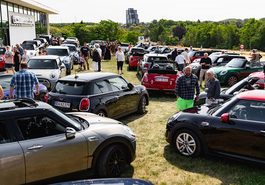 Interesserede MINI-kunder gående rundt blandt MINI modeller på græsplæne foran Bayern AutoGroup