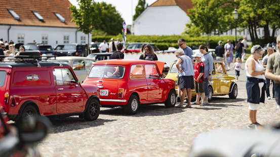 Personer kigger på ældre MINI'er parkeret.