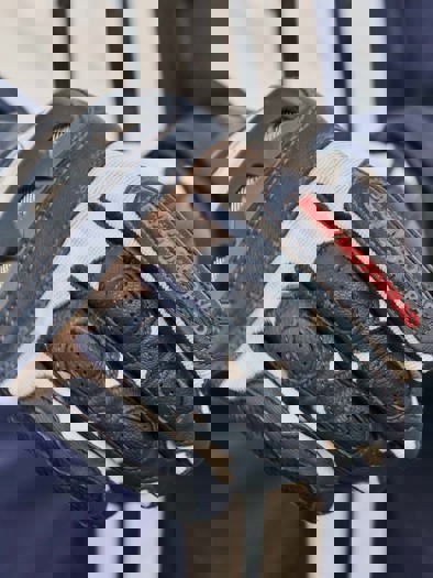 Et nærbillede af en hvid og sort motorcykelhandske, med BMW Motorrad Logo i rød på pegefingeren.