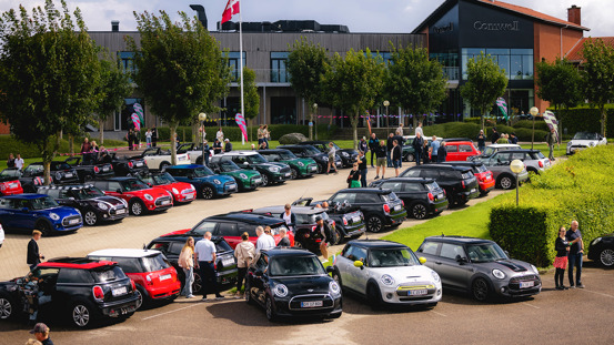 Fyldt parkeringsplads med MINI'er og mennesker.