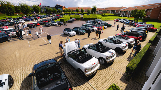 Fyldt parkeringsplads med MINI'er og mennesker.