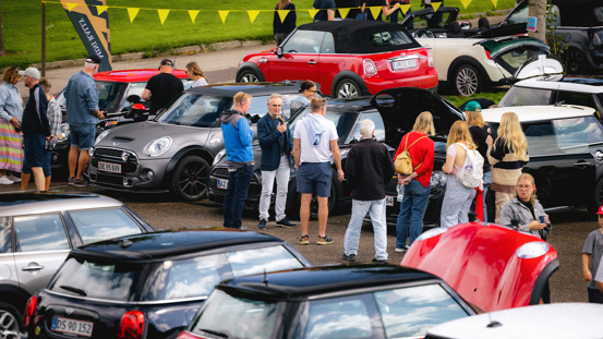 Fyldt parkeringsplads med MINI'er og mennesker.