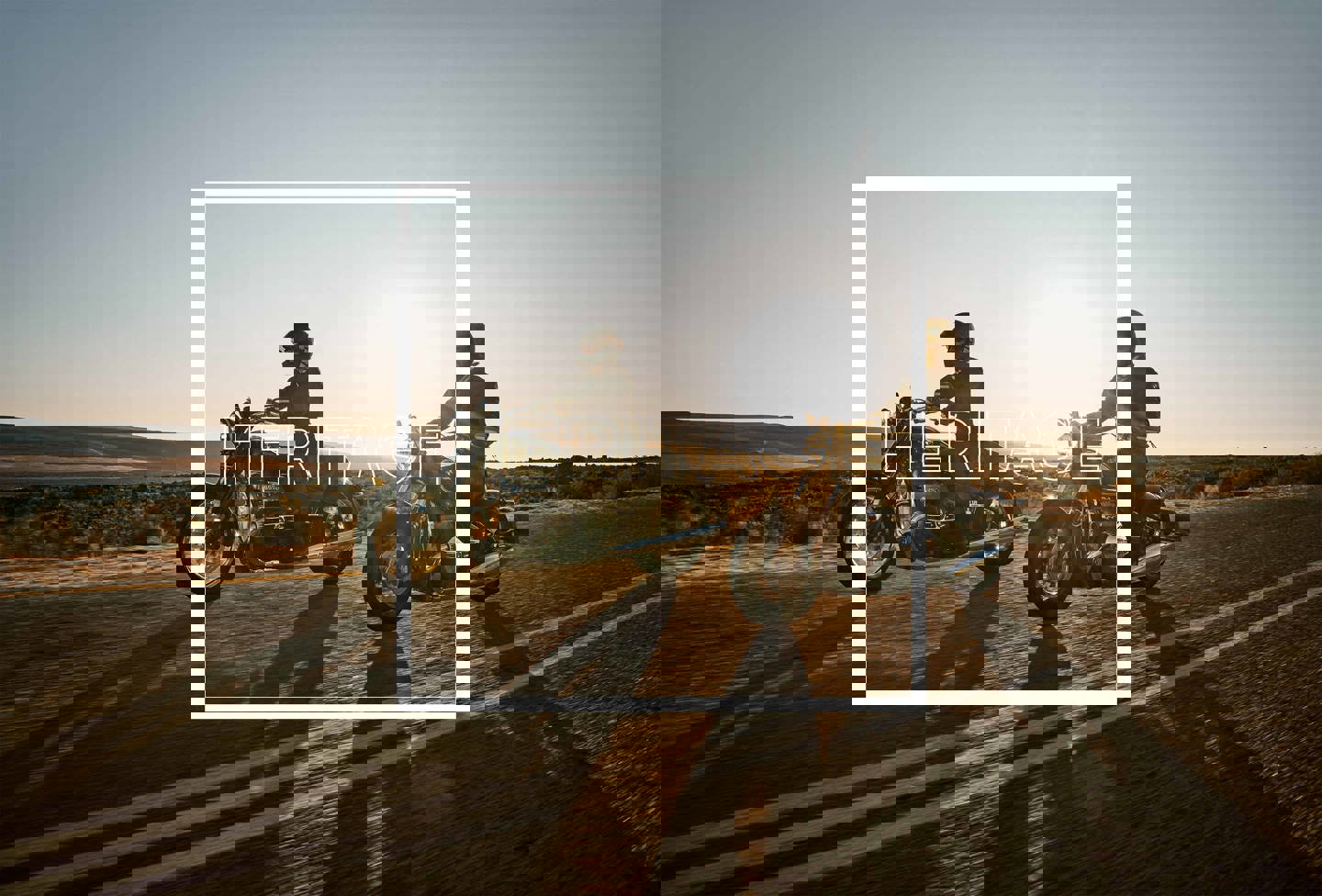 To personer kører på motorcykel på en landevej ved solnedgang. På billedet står ordet HERITAGE i hvid. 