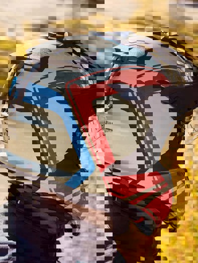 Et nærbillede af en person med en hvid, rød og blå motorcykelhjem på, set fra siden.