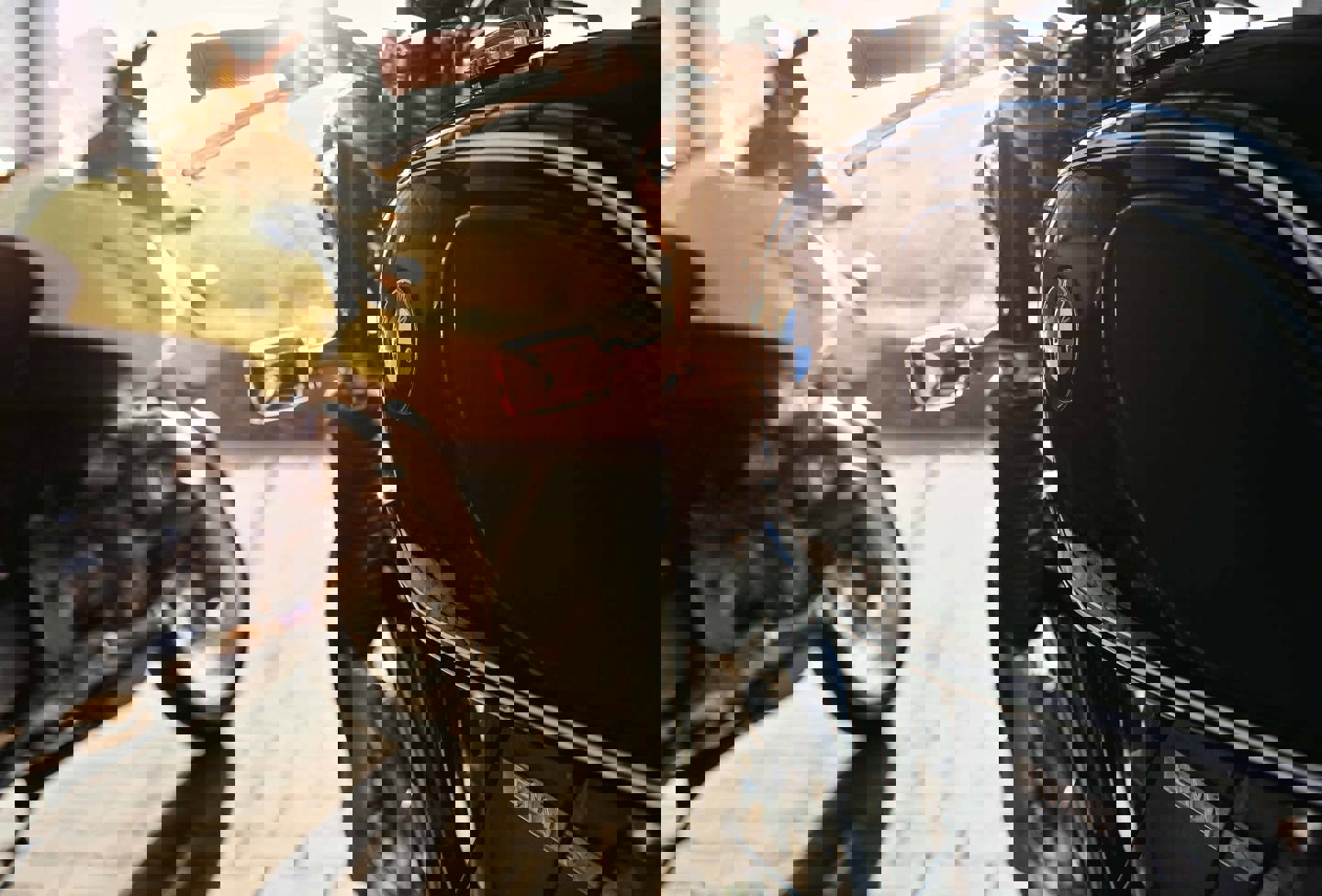 En person cykler på en gade i byen med biler og træer i baggrunden.